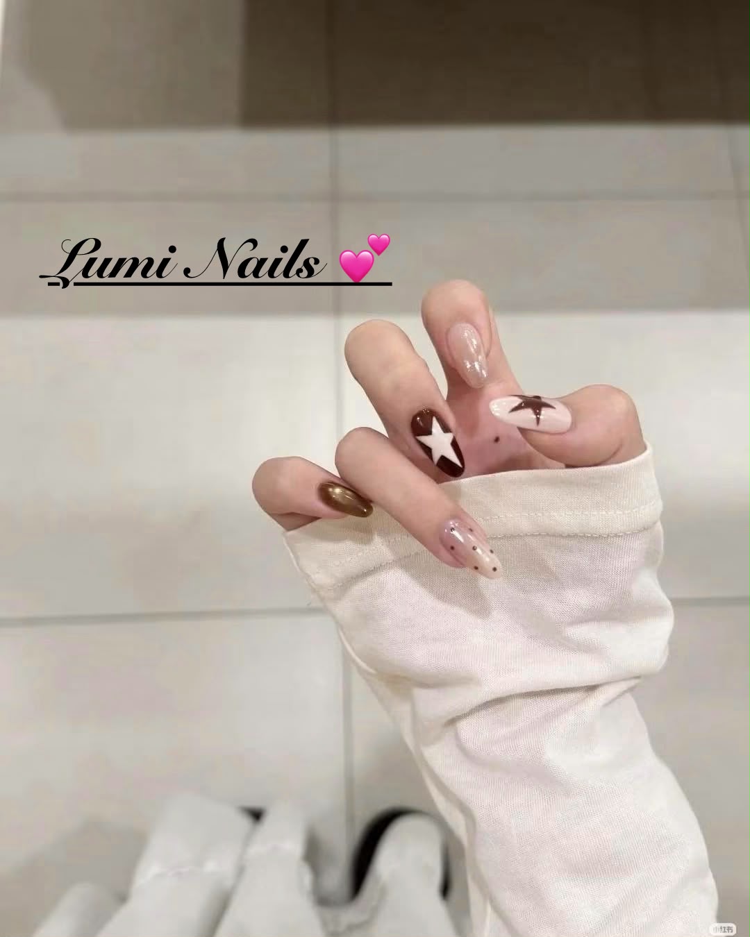 Glanzende nude nagels met bruine sterren en metallic accenten